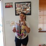 Smiling woman wearing playful glasses and holding a “Math” sign at a school-themed photo booth.